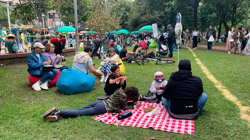 Muchas personas, en diferentes lugares de un parque, haciendo pícnic.