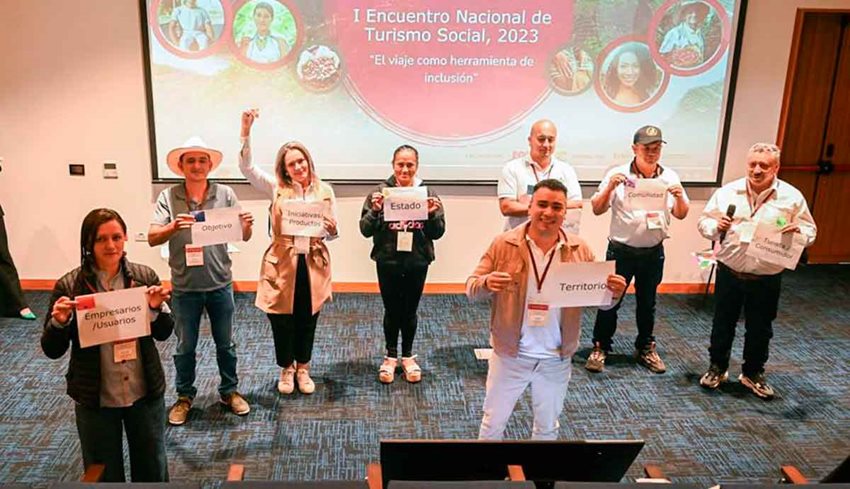 Hombres y mujeres de pie en el escenario sosteniendo letreros.